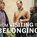 From Visiting to Belonging - group of men at church talking and joking around