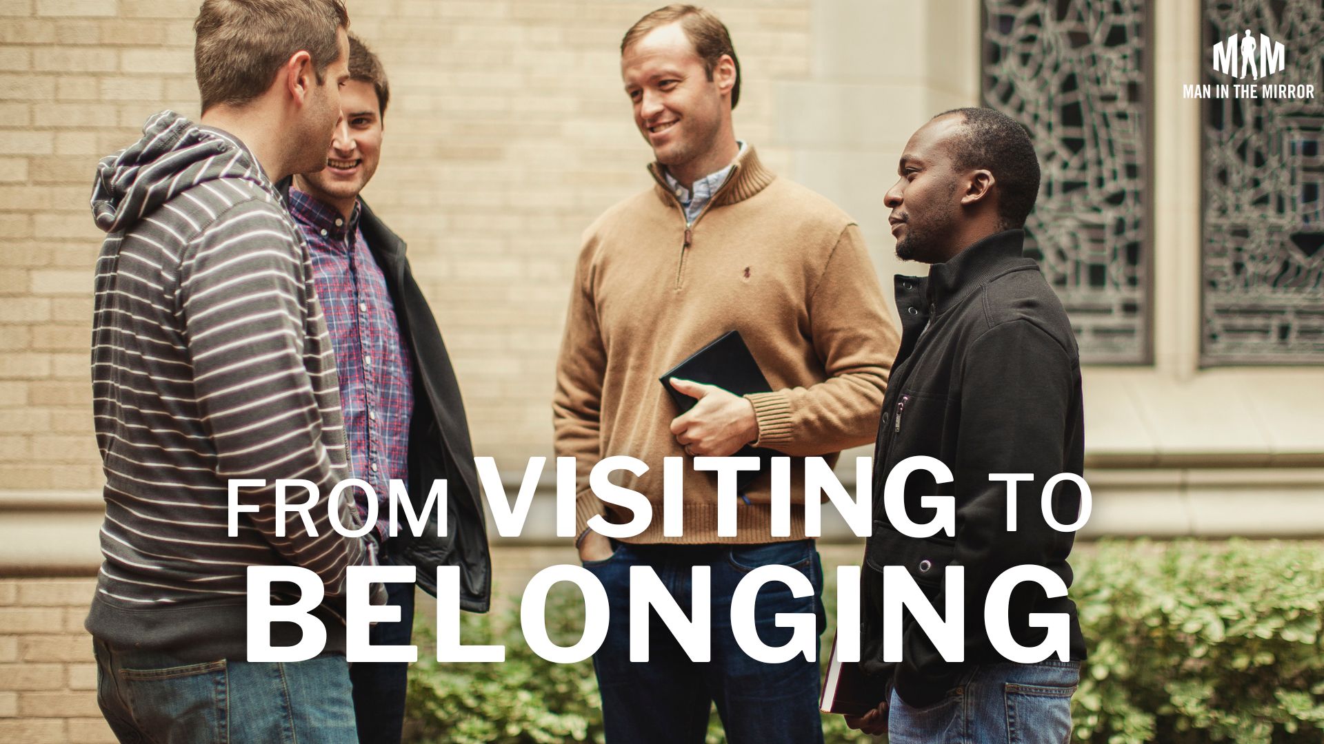 From Visiting to Belonging - group of men at church talking and joking around